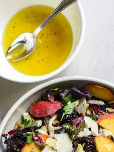 a bowl of salad next to a bowl of dressing