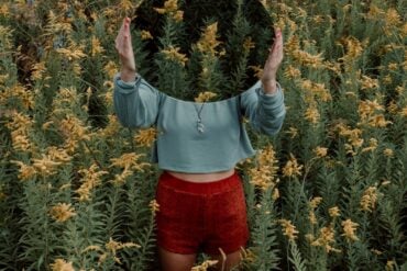 standing woman surrounded by yellow flower field during daytime